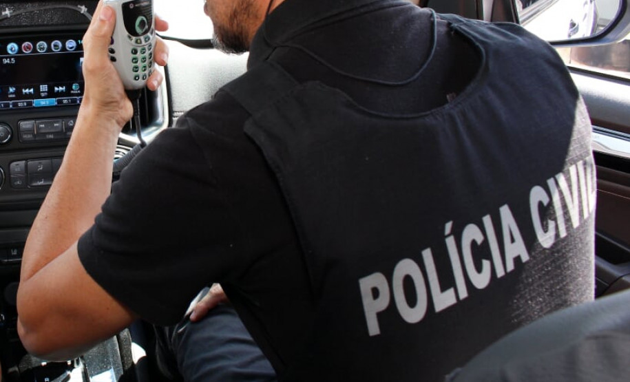 Policial civil no interior de uma viatura, falando ao rádio