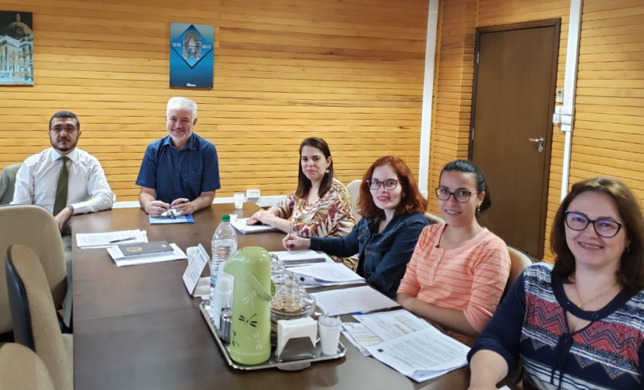 Participantes reunidos à mesa, para discutir o cronograma