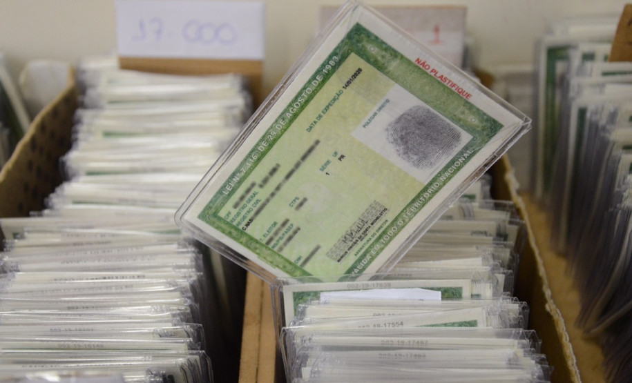 Centenas de documentos em caixas, com um RG em destaque