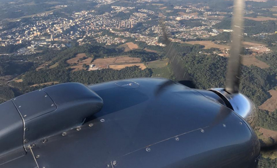 Detalhe da hélice de aeronave. Ao fundo, espaço urbano