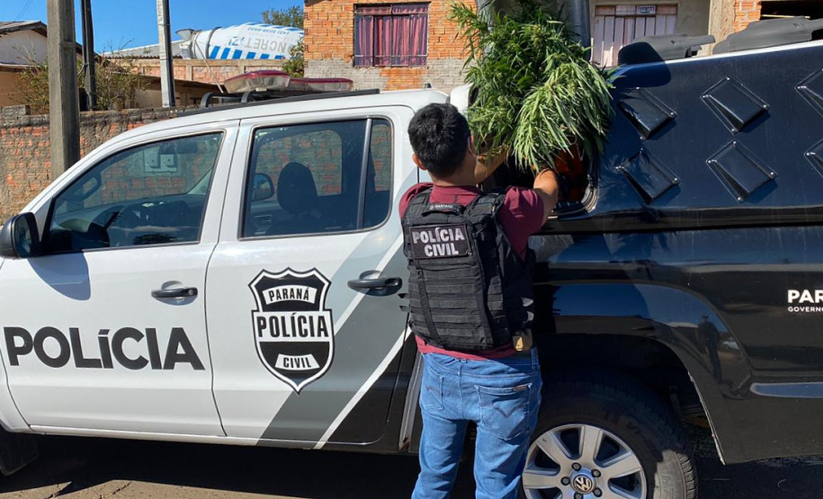 Policial recolhendo em viatura material apreendido