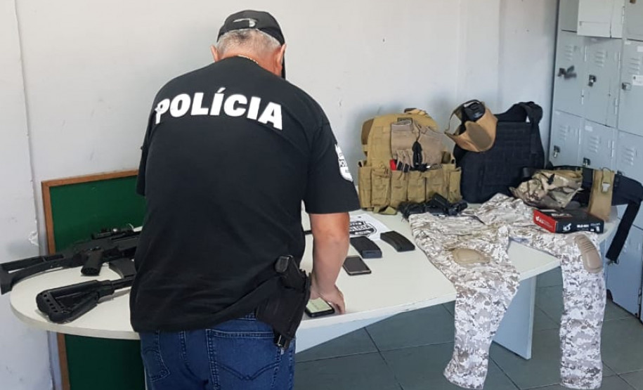 Policial civil organizando sobre uma mesa o material apreendido