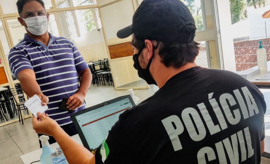Policial civil consultando carteira de vacinação