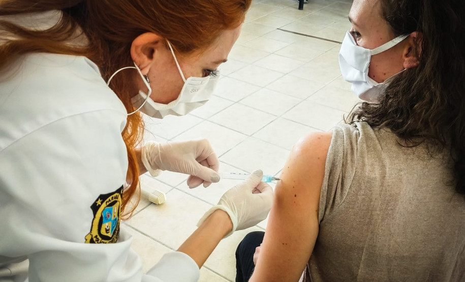 Policial aplicando vacina no braço de uma mulher