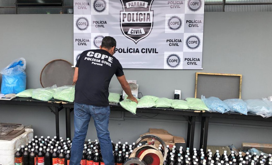 Policial civil agrupando material apreendido sobre uma mesa