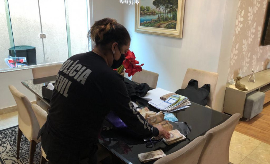 Policiais civis cumprindo mandado de busca e apreensão em endereço relacionados a investigados por estelionato