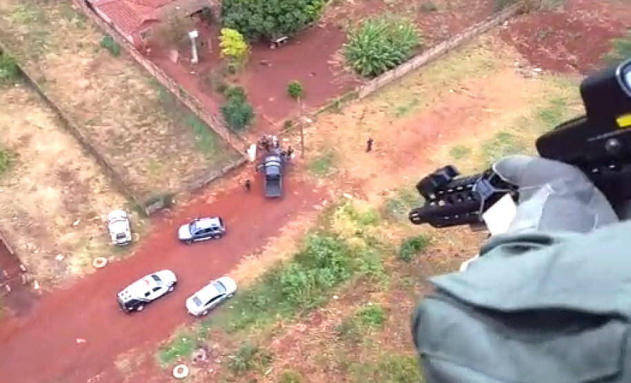 Policial civil em helicóptero acompanhando operação de policiais em terra