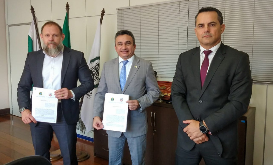 Delegado-geral e superintendente da CGU apresentando documento assinado. Junto, chefe da divisão de combate à corrupção.