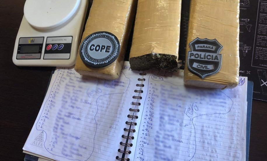 Tabletes de droga, balança e um caderno com anotações