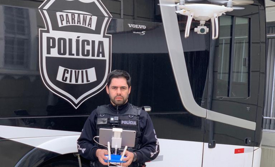 Investigador Juliano Filtrado operando um drone ao lado de ônibus da Policia Civil