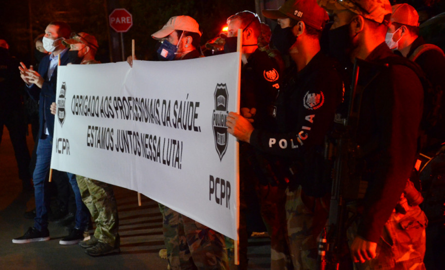 Policiais civis segurando faixa homenageando os profissionais da saúde