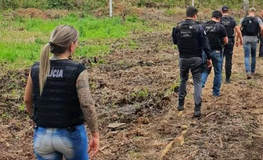 Policiais civis caminhando por uma área rural