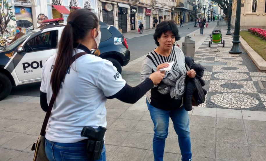 Policial civil entregando máscara para transeunte