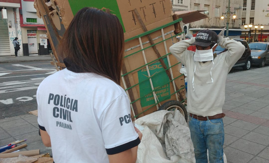 Policial civil observa transeunte colocando máscara