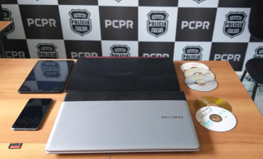 Notebooks, celulares e cds apreendidos, sobre uma mesa