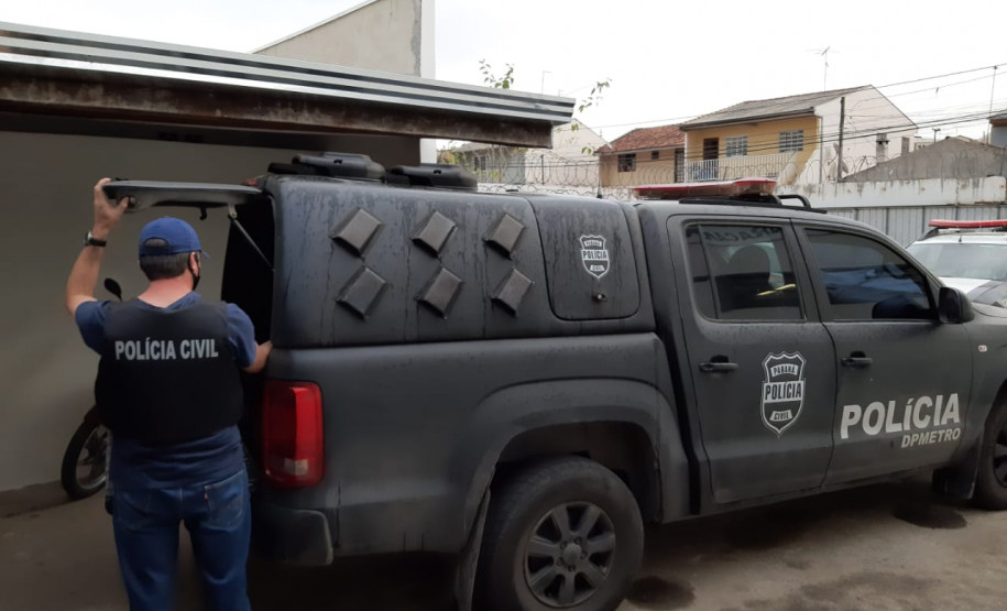 Policial civil segurando tampa de porta-malas de viatura