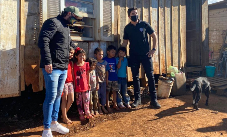 Policiais civis junto a criancas da localidade, posando para foto