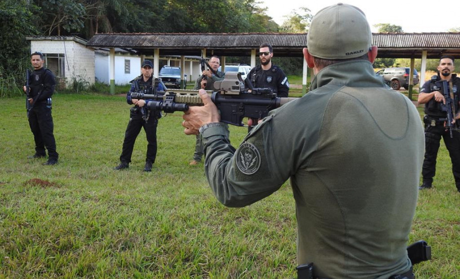 Policial civil apontando fuzil enquanto fala com alunos