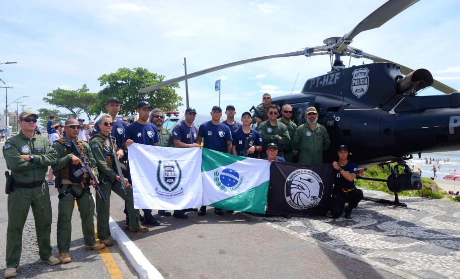 Integrantes do GOA segurando bandeiras, junto a helicóptero