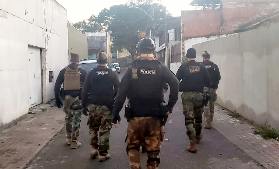 Vários policiais andando na rua, em frente ao local