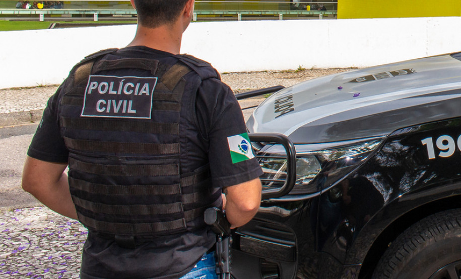 Policial civil ao lado de viatura
