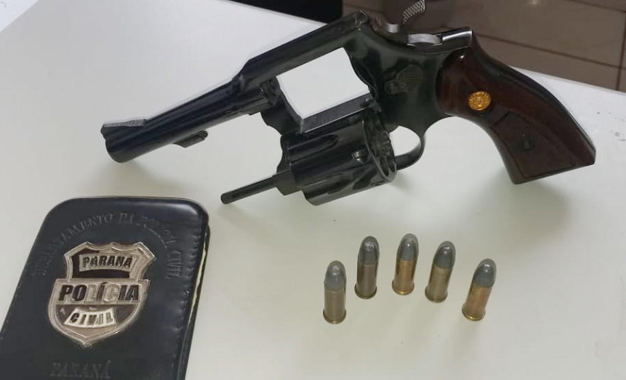 Arma, munições e carteira da polícia sobre uma mesa