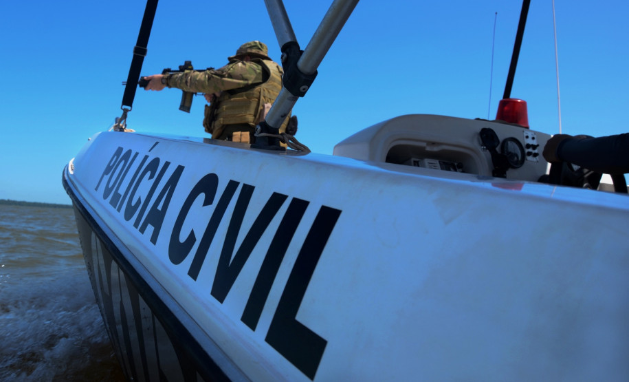 No interior de um barco da polícia civil, policial aponta arma
