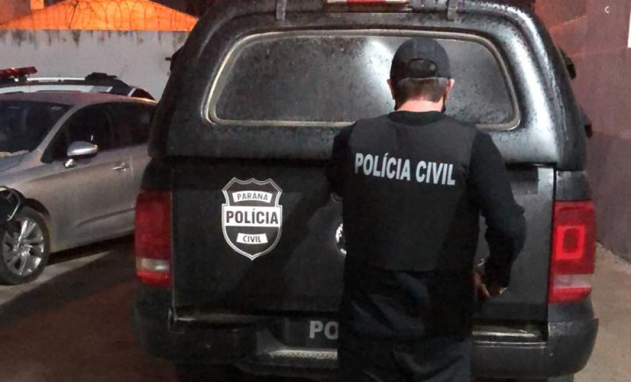 Policial civil de costas, ao lado de viatura