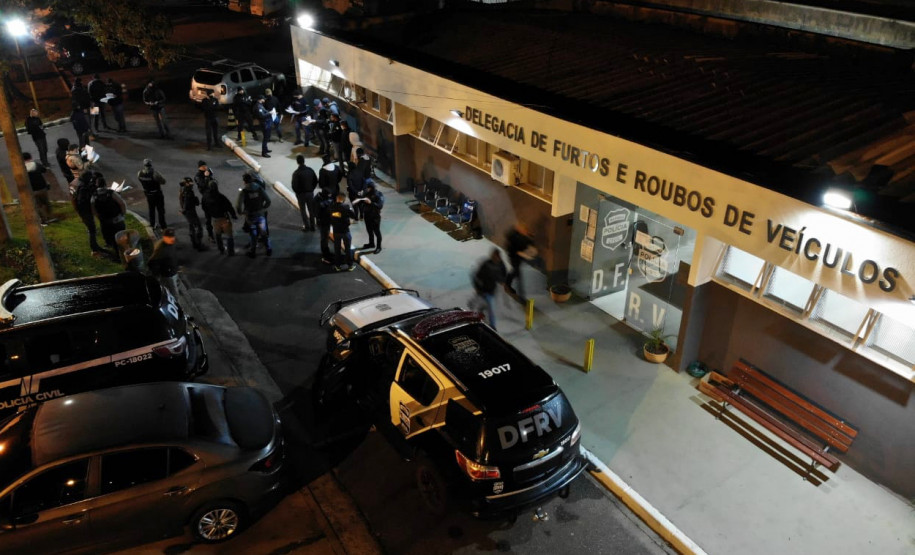 Foto aérea, com policiais reunidos em frente à delegacia