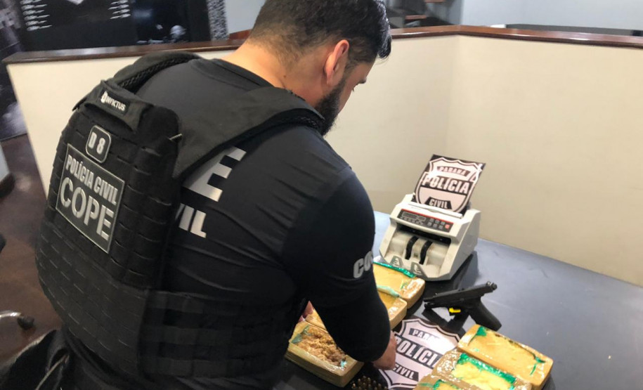 Policial civil organiza material apreendido, sobre uma mesa