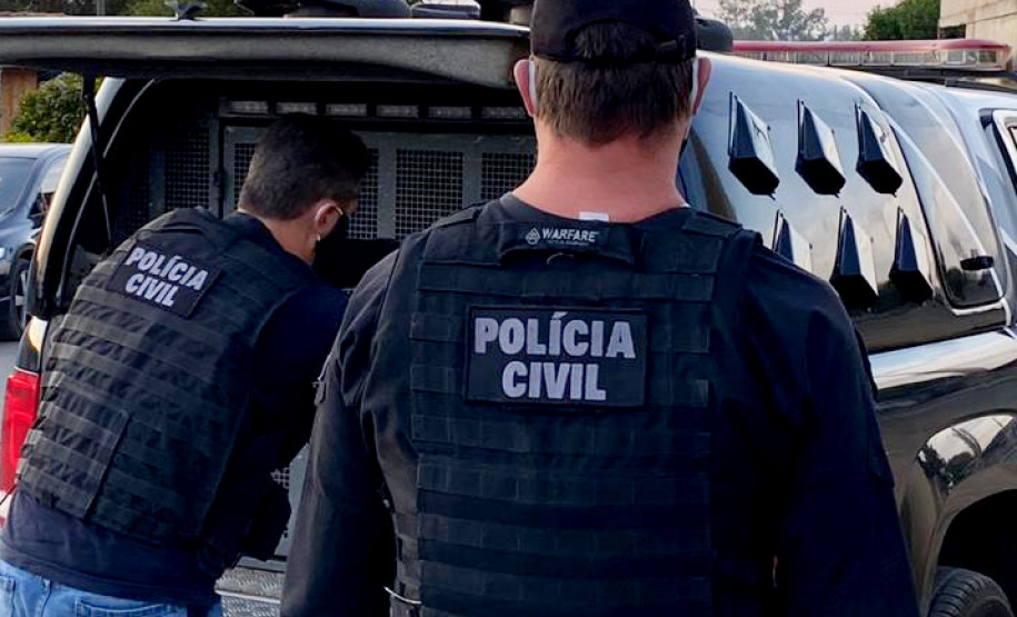 Dois policiais civis atras de uma viatura com o porta-malas aberto