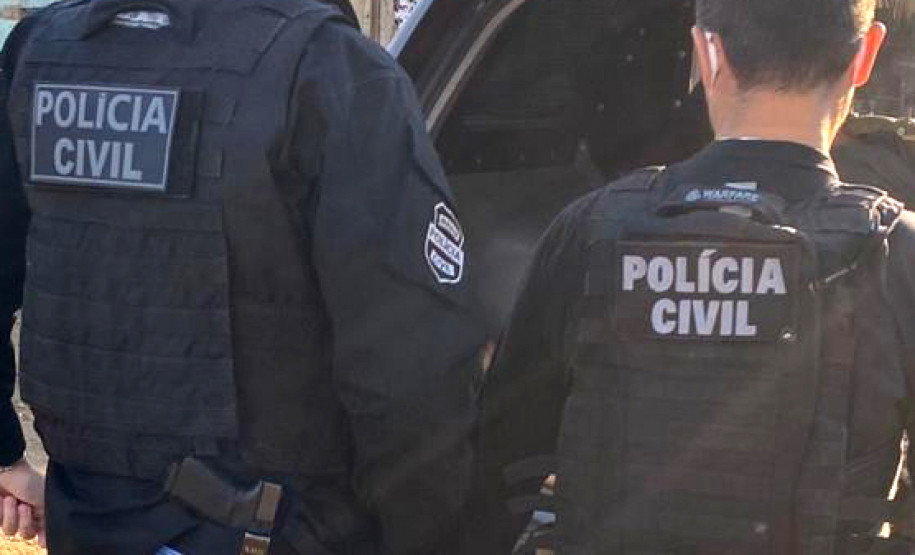 Dois policiais civis ao lado de viatura