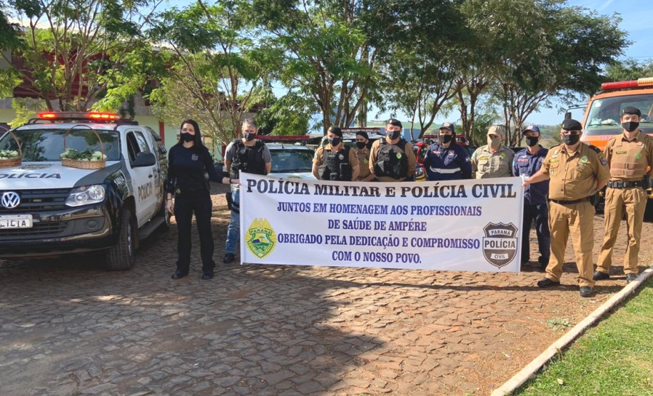 Policiais civis, bombeiros e policiais militares segurando uma faixa com homenagem