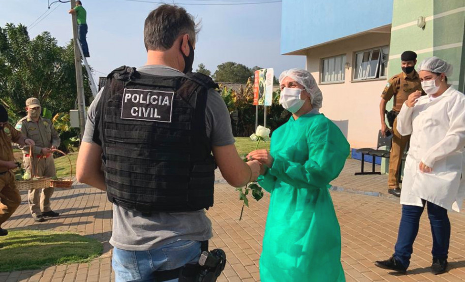 Policial civil entregando uma flor a uma profissional da saúde
