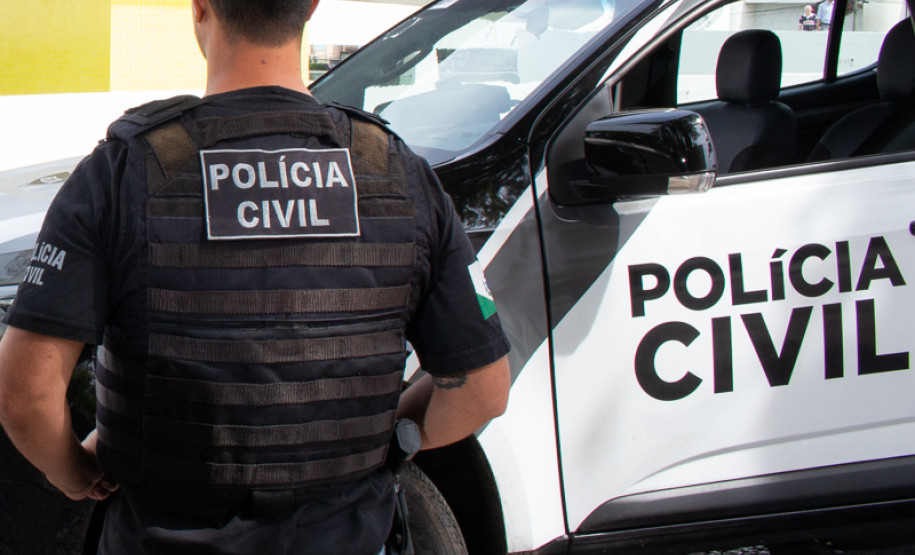 Policial civil ao lado de viatura