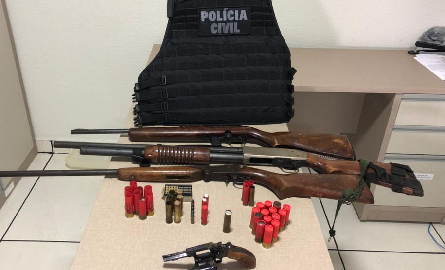 Armas, munição apreendida e colete da polícia, sobre uma mesa