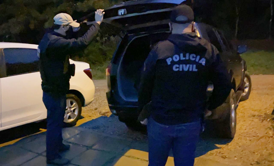 Policiais civis ao lado de viatura