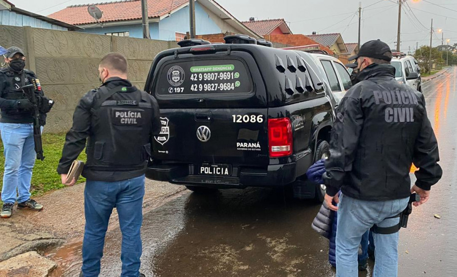 Policiais civis ao lado de viatura