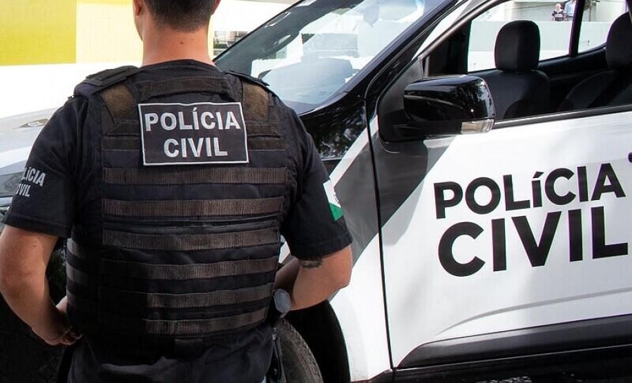 Policial de costas, ao lado de viatura
