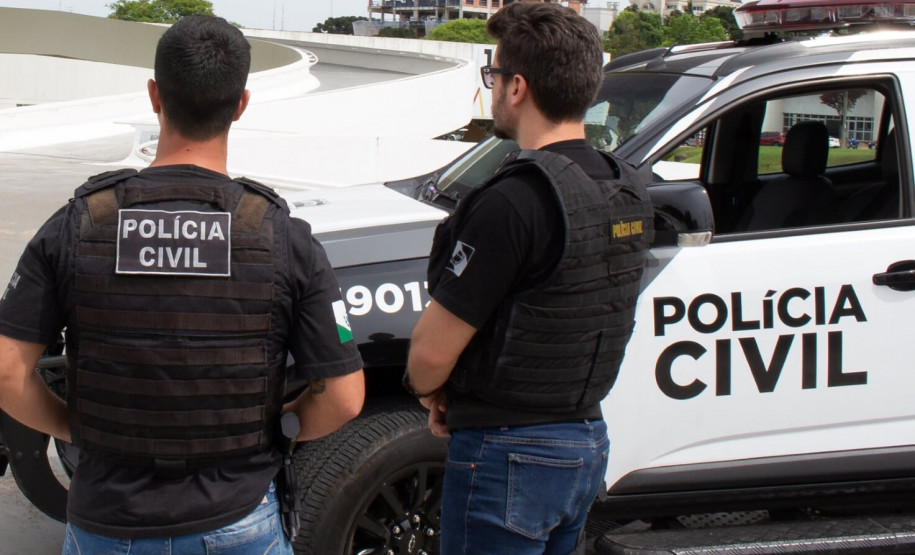 Policiais civis ao lado de viatura