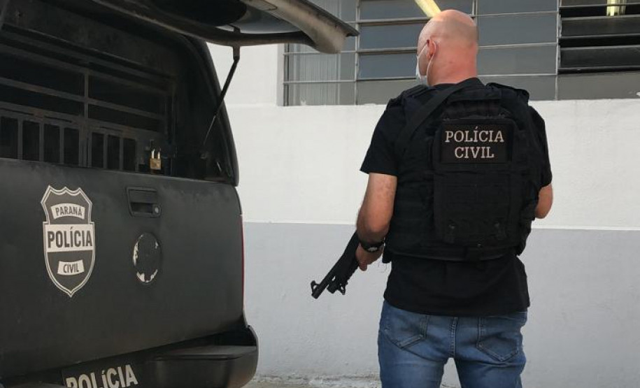 Policial civil ao lado de viatura