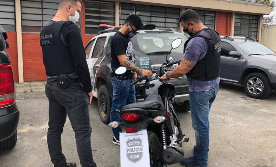 Policiais observam moto recuperada