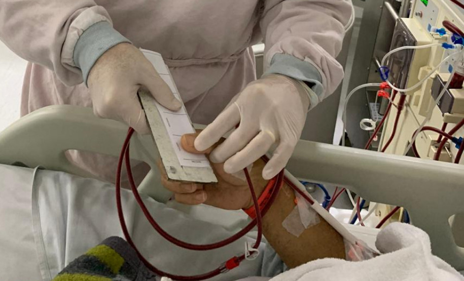 Policial colhendo impressao digital de pessoa deitada em cama de hospital