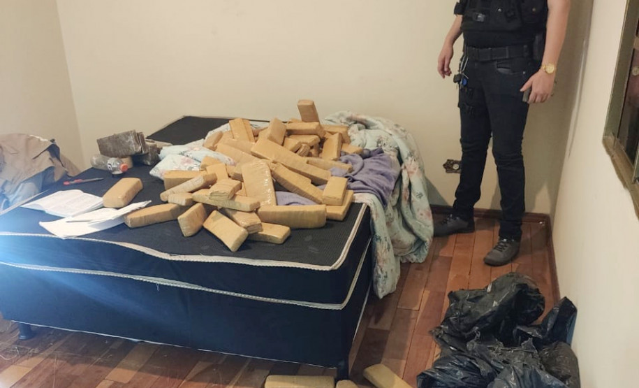 Policial observa diversos tabletes de droga espalhados em um cômodo