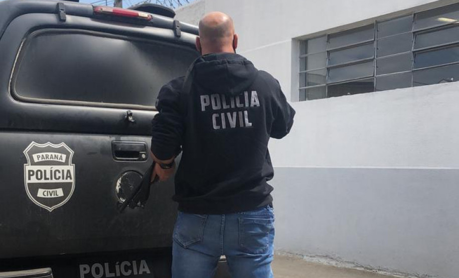 Policial civil empunhando arma ao lado de viatura