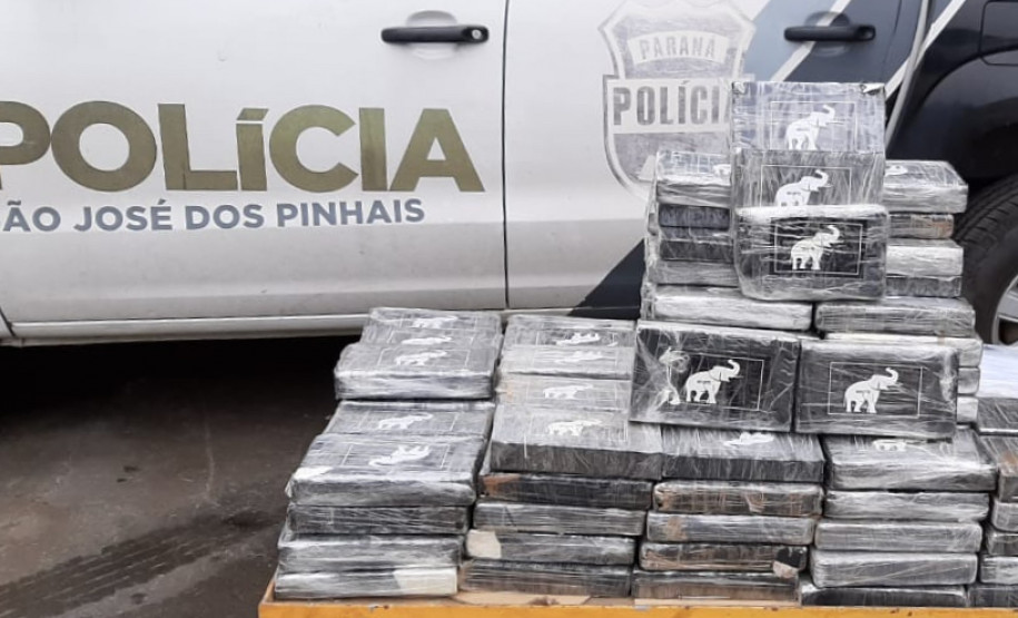 Tabletes de droga empilhados ao lado de uma viatura