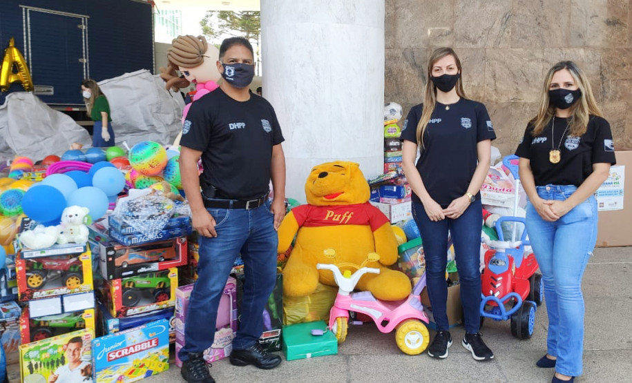 Policiais civis posando para foto junto a brinquedos doados