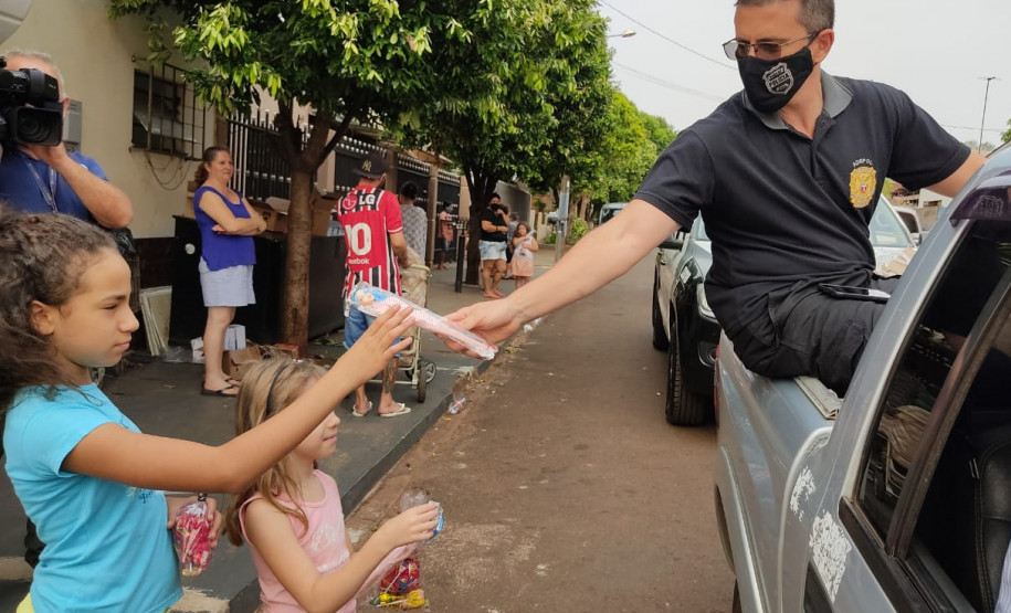 Policial em carroceria de veículo entregando brinquedo à criança