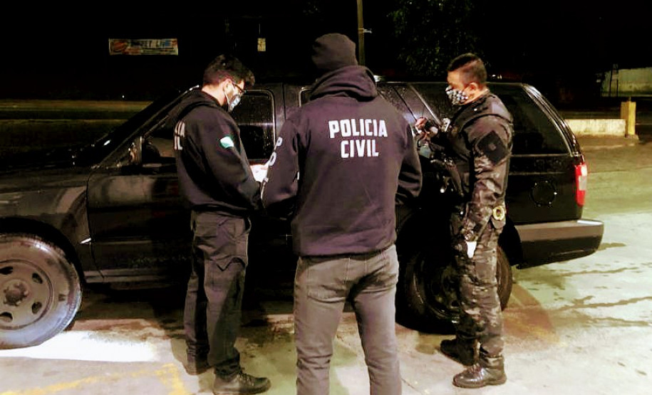 Policiais civis reunidos, ao lado de viatura