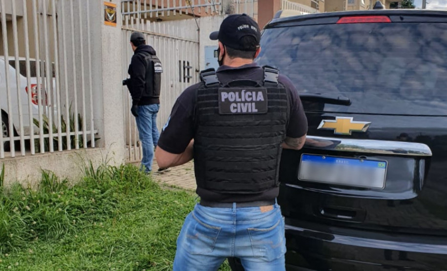 Policiais civis na calçada, em frente ao local de busca